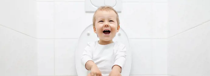 smiling child sitting on the toilet