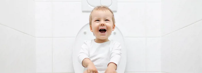 smiling child sitting on the toilet