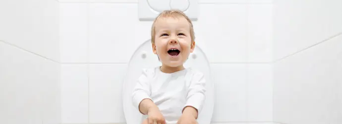 smiling child sitting on the toilet