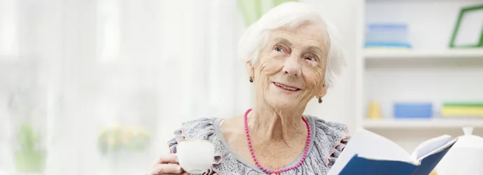 Old lady holding a cup and a blue-covered book