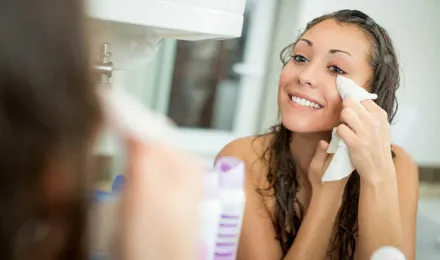 Woman smiling while removing makeup with a facial wipe