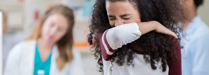 Girl sneezing into her arm