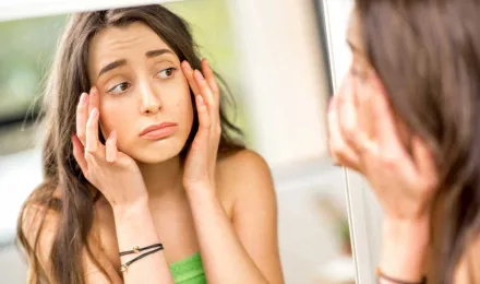 Teenager checking her swollen eyes from allergies in the mirror