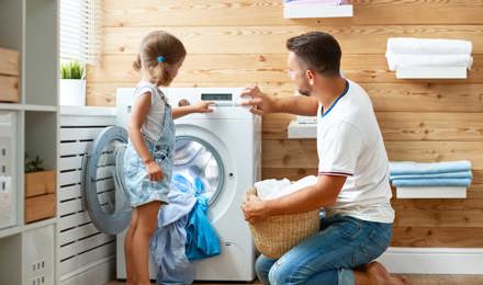 Father and child daughter doing laundry together in a fun kids laundry time