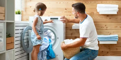 Father and child daughter doing laundry together in a fun kids laundry time