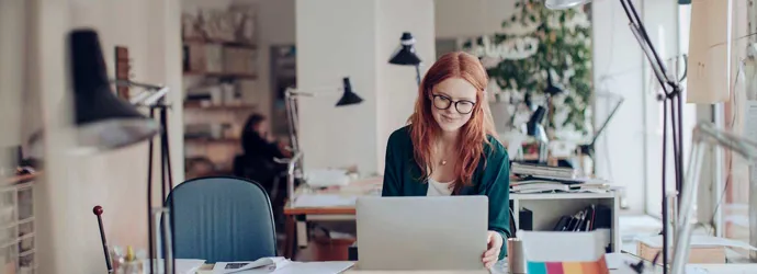 A woman working in her laptop sitting at her desk