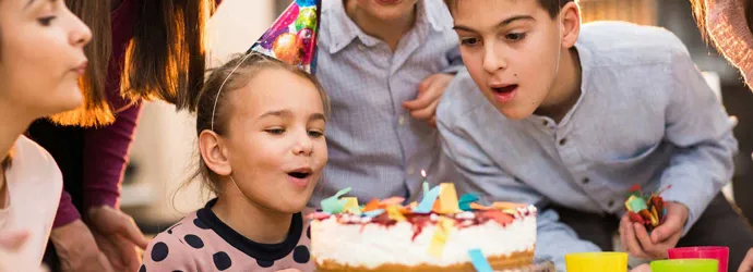 Children standing around a cake on a kids birthday party