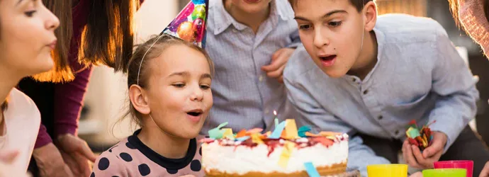 Children standing around a cake on a kids birthday party