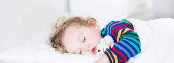 Toddler girl sleeping on a bed