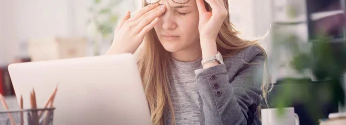 Young woman suffering from eye strain while working on a laptop which is one of the causes of watery eyes