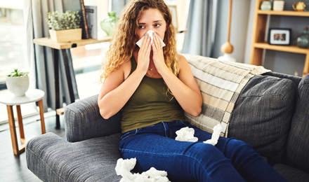 Woman with cold allergy symptoms blowing her nose