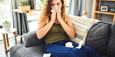 Woman with cold allergy symptoms blowing her nose
