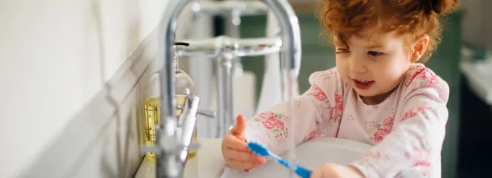 A mother helping her daughter and son washing their hands in the kitchen