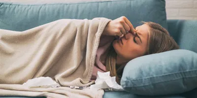 Woman lying in a blue sofa feeling sinus pain