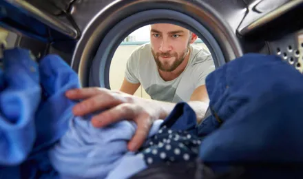 Man reaching for clothes inside the washing machine
