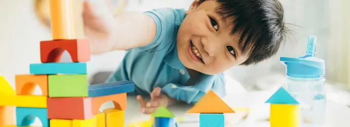 A young boy playing with colourful wooden toys